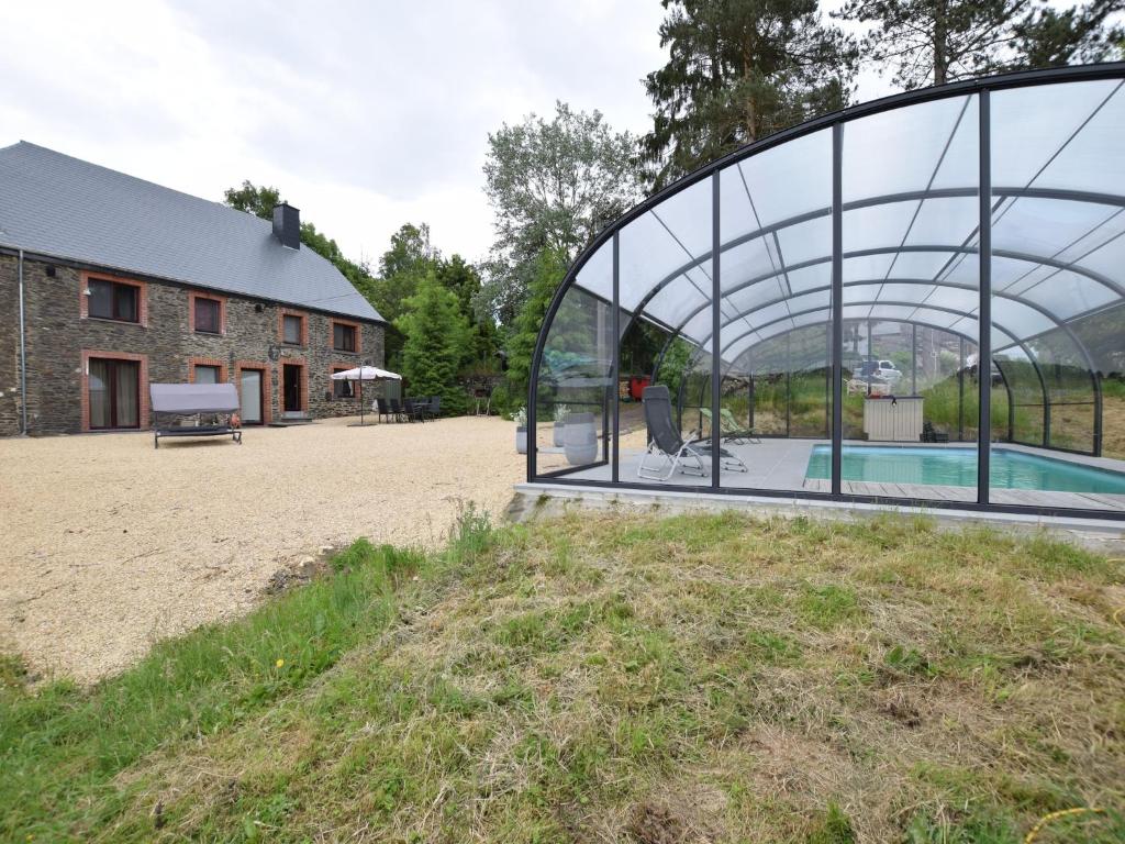 a glass house with a pool in front of a house at Cottage in Ardennes with Heated Pool in Warempage