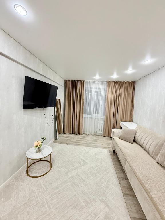 ein Wohnzimmer mit Sofa und Fernseher in der Unterkunft 1,5-комнатная квартира в центре города in Öskemen