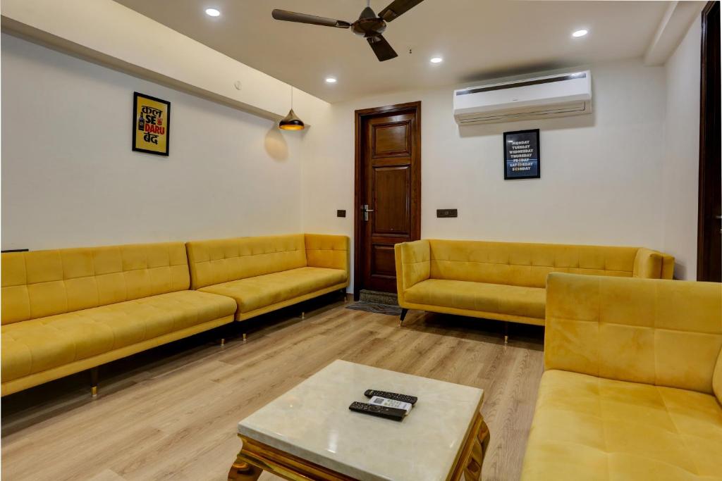 a waiting room with yellow couches and a table at Hotel O Golden Eye Inn in New Delhi