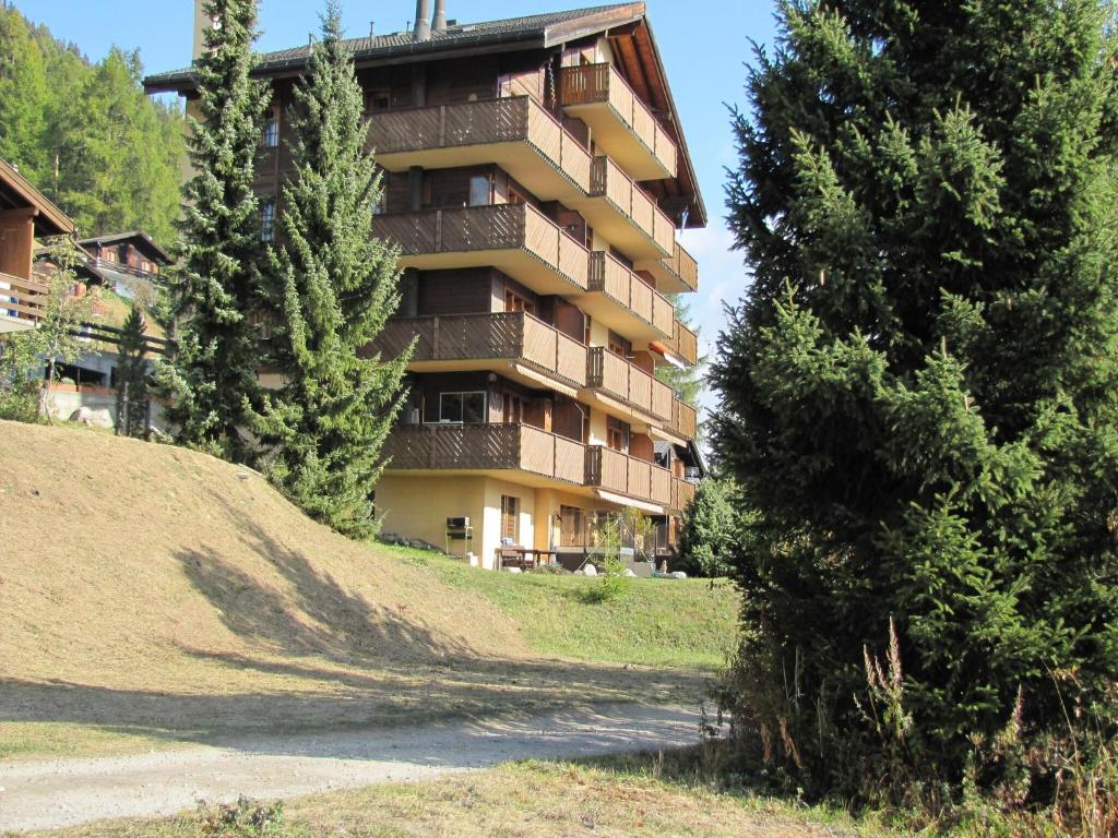 a tall apartment building on a hill with trees at Family Stay in Aletsch Alps in Bellwald