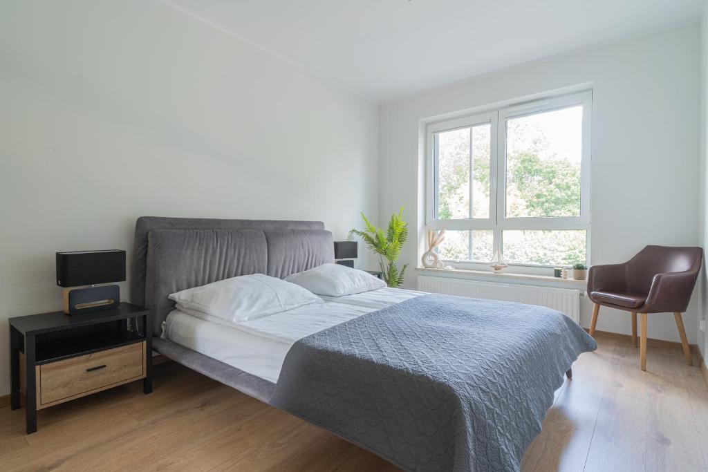 a bedroom with a bed and a chair and a window at Apartament MK Sosnowskiego 9 in Białystok