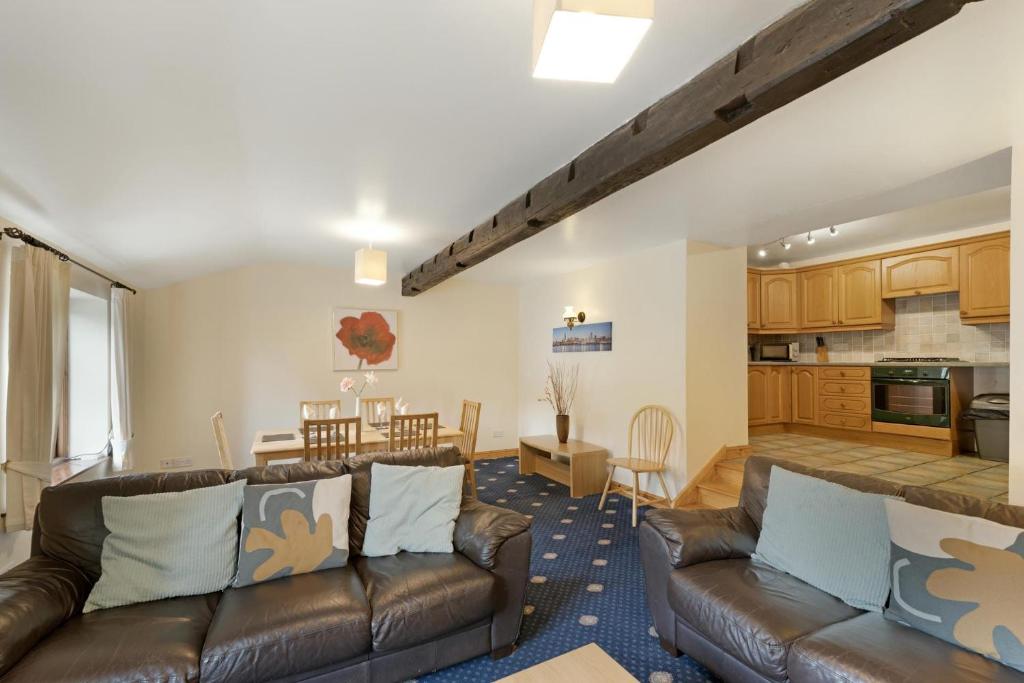 a living room with two leather couches and a kitchen at Bank View Barn at Pound Farm in Crook