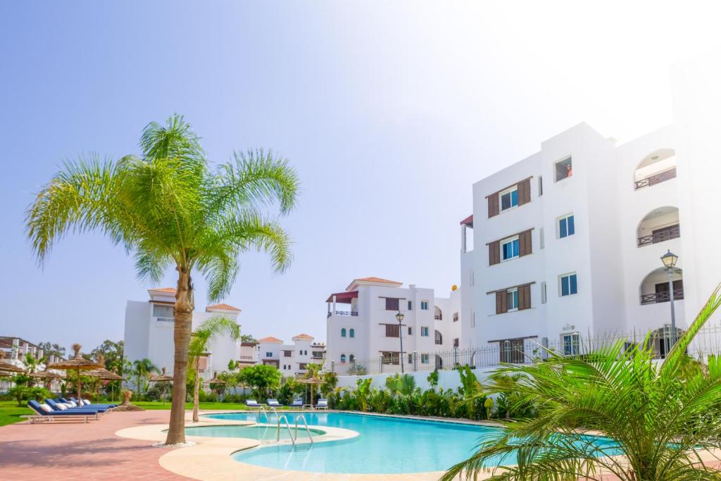 a resort with a swimming pool with palm trees and buildings at Valeria Kasbah Del Mar in Cabo Negro