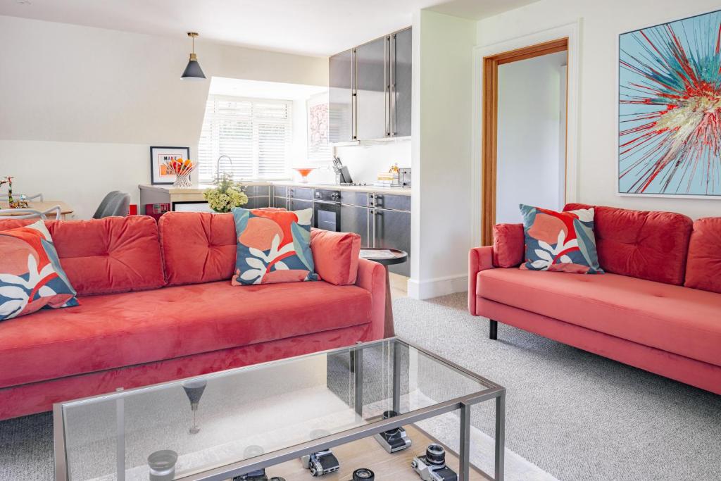 ein Wohnzimmer mit zwei roten Sofas und eine Küche in der Unterkunft The Flat - Waresley Park Estate 
