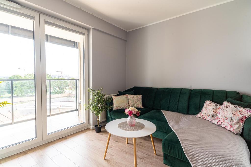 a living room with a green couch and a table at Apartament MOJA MŁYNOWA in Białystok