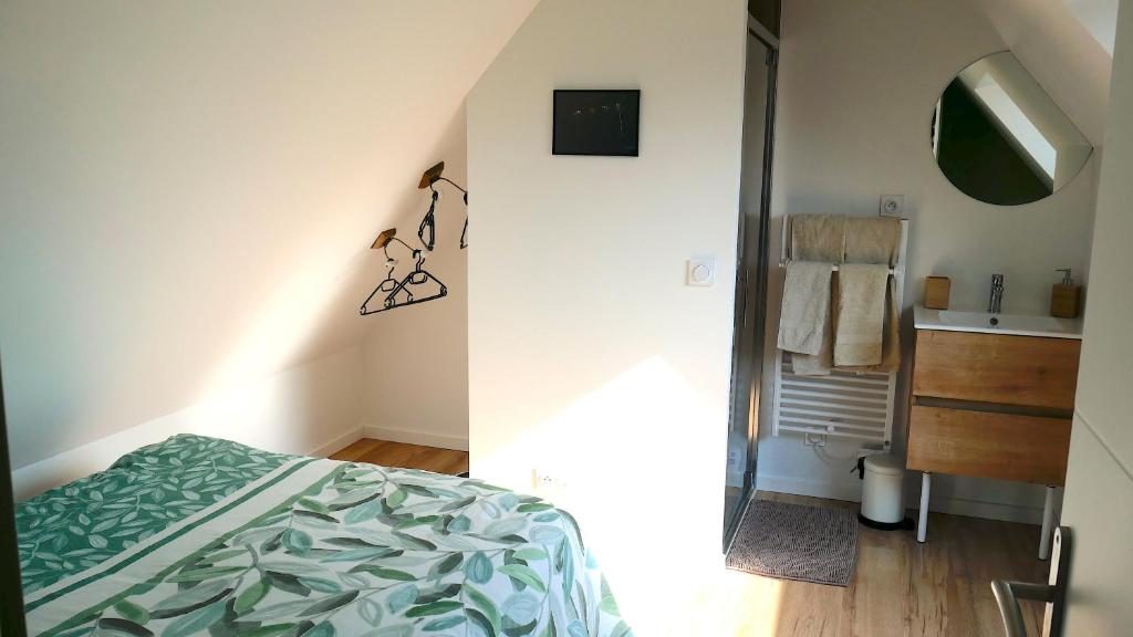 una camera da letto con un letto, un lavandino e uno specchio di Maison des Hirondelles a Yvré-lʼÉvêque