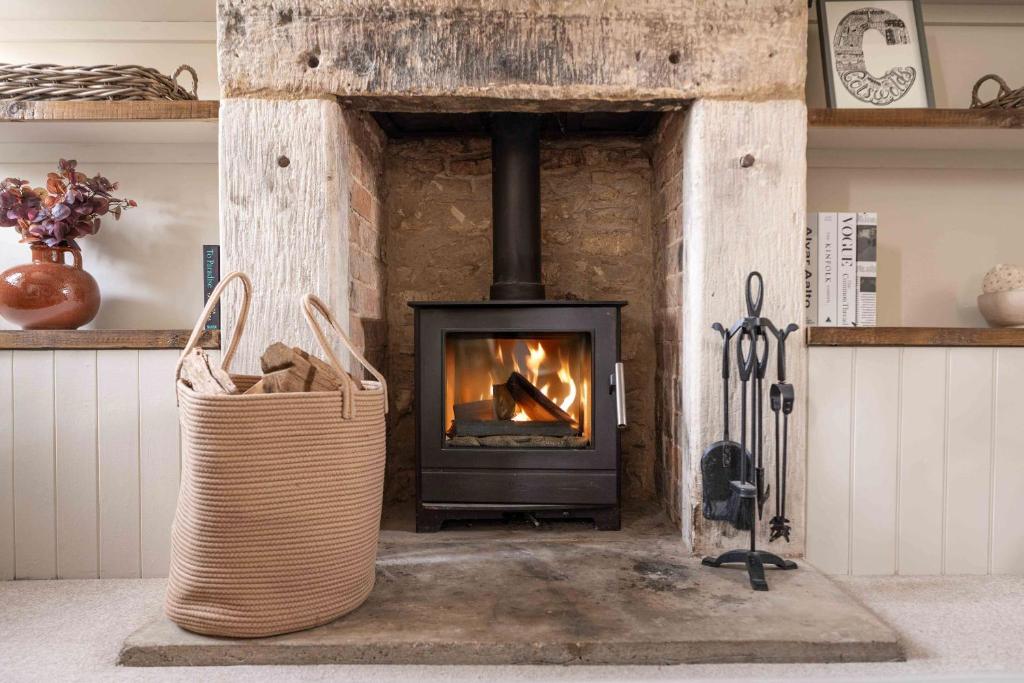 a brick fireplace with a stove in a room at The Lantern in Bourton on the Water