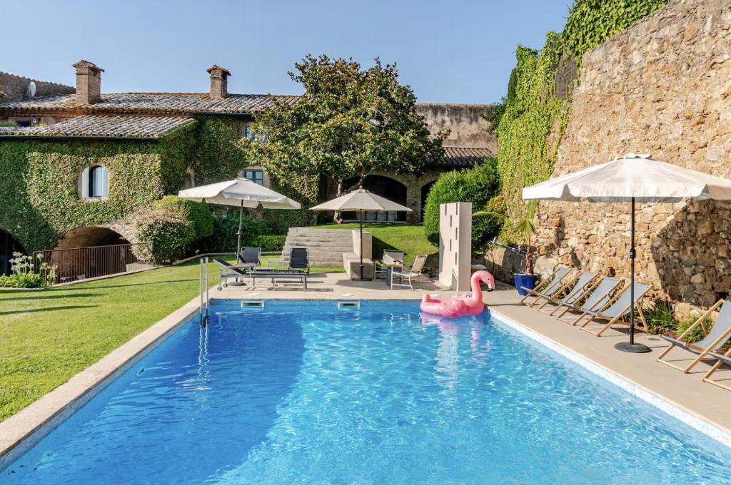a swimming pool with a pink flamingo in a yard at Casa Rufina, Exclusive & Charming Stone House in Costa Brava in Pals