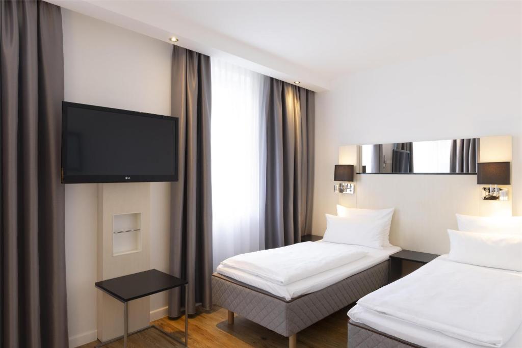 Una habitación de hotel con dos camas y un televisor de pantalla plana. en Scandic Berlin Kurfürstendamm, en Berlín