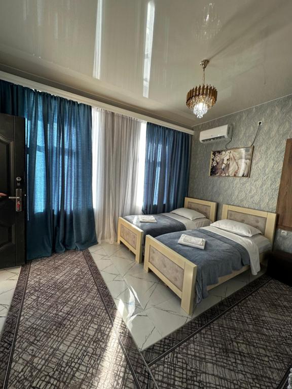 two beds in a bedroom with blue curtains at Chelo Guest House in Kutaisi