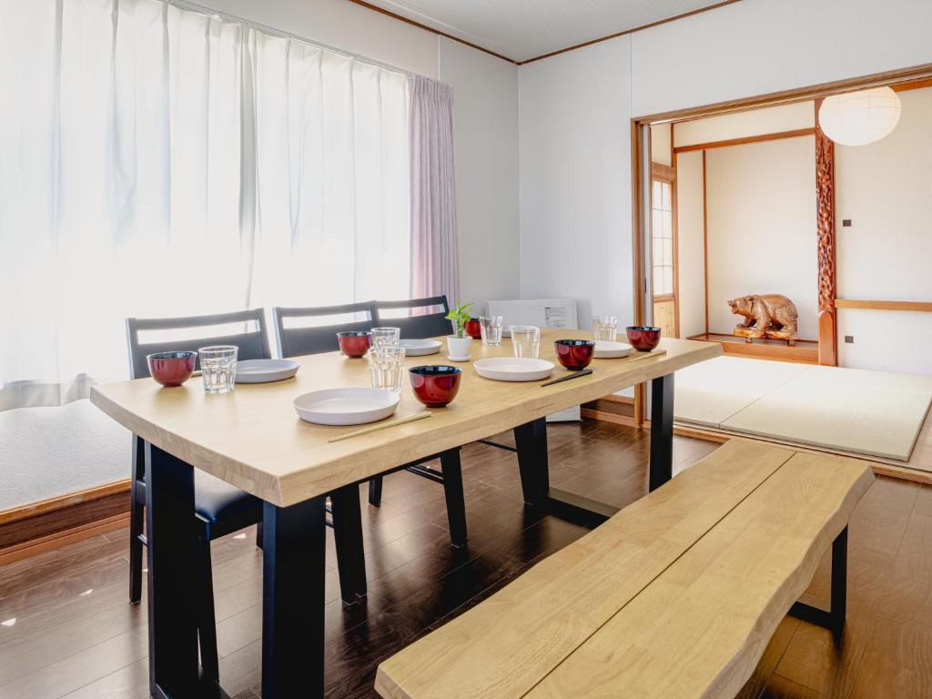 a dining room with a wooden table and benches at Shishimai Kushiro in Kushiro