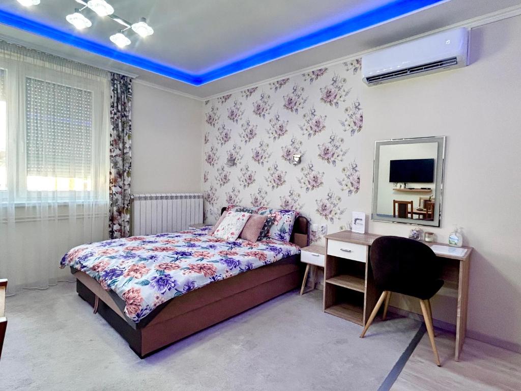 a bedroom with a bed and a desk and a mirror at Belien Apartman in Makó