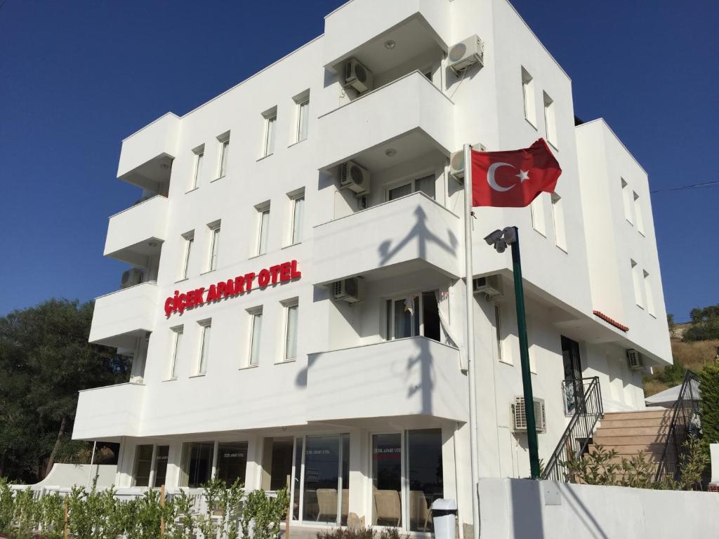 a white building with a flag in front of it at Cicek Apart Hotel in Cesme