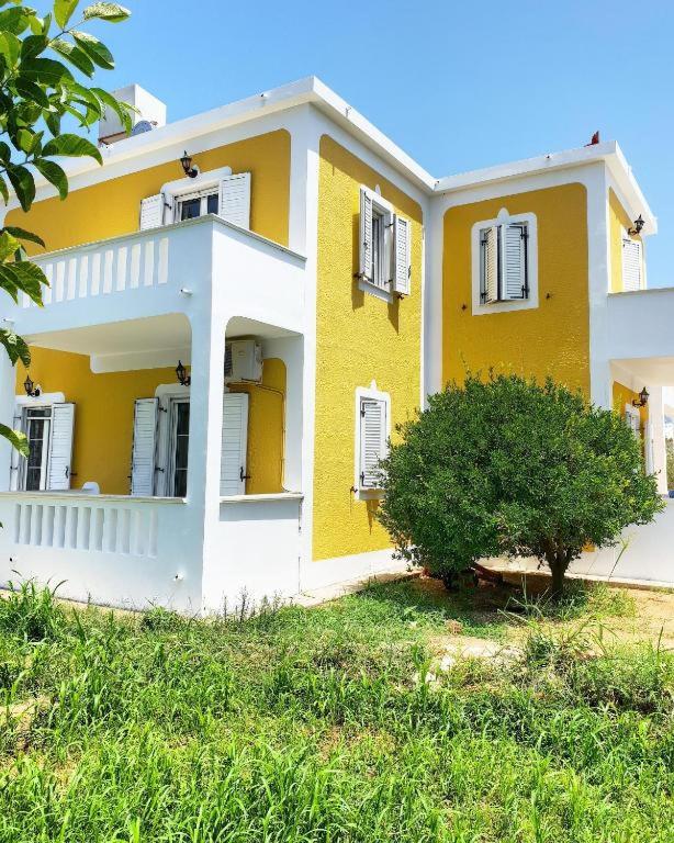 a yellow house with a tree in front of it at Villa Angeliki II in Kámpos