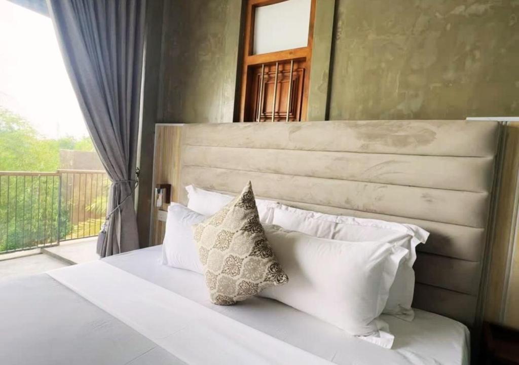 a bedroom with a white bed with pillows and a window at Diyakawa Boutique Hotel in Anuradhapura