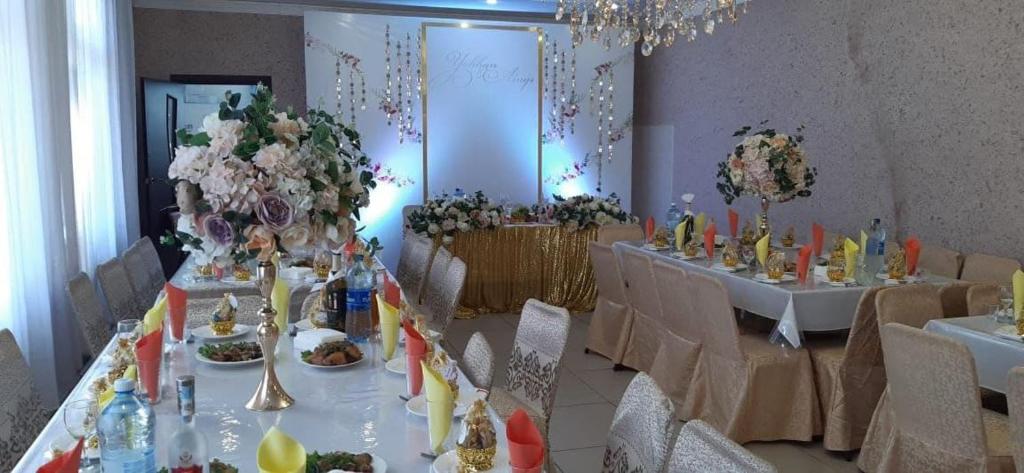 a dining room with two tables with food and flowers at Банкетный зал для любых мероприятий in Petropavlovsk