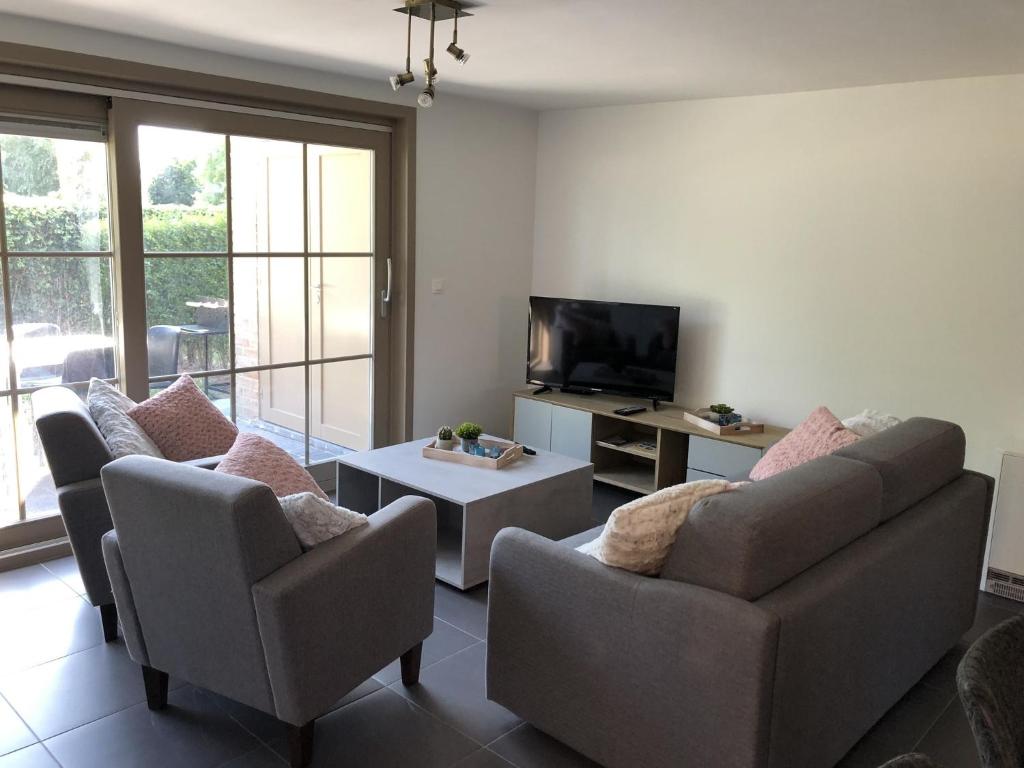 a living room with two couches and a tv at Bright Family Stay with Bikes in De Panne