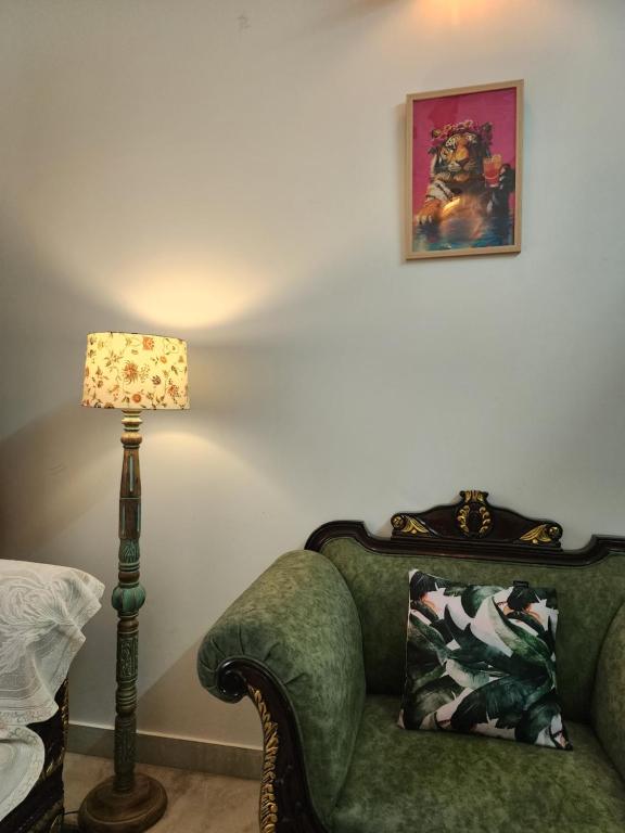 a living room with a green chair and a lamp at Owee Stays - A stay with more stories in Jaipur