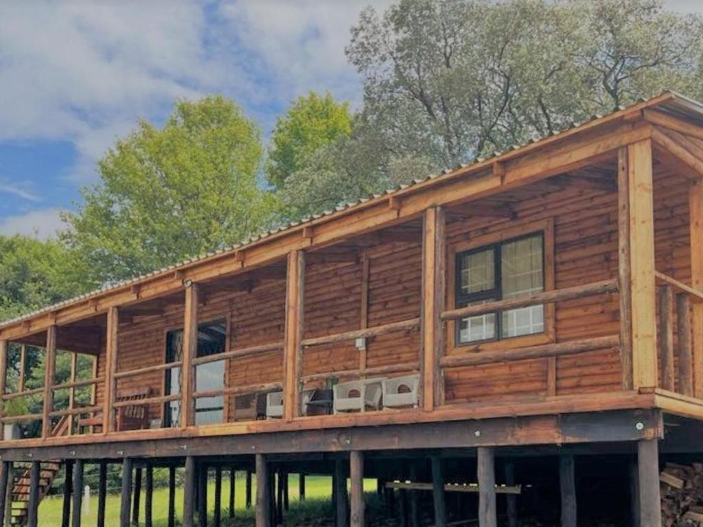 a log home with windows and trees in the background at Fireside Cabin in Underberg