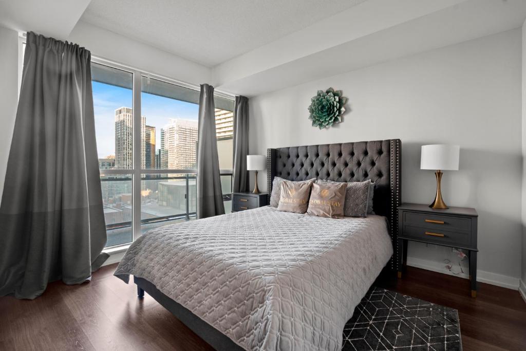 een slaapkamer met een groot bed en een groot raam bij Modern 1Bd & Den Condo with Balcony Lillian St in Toronto