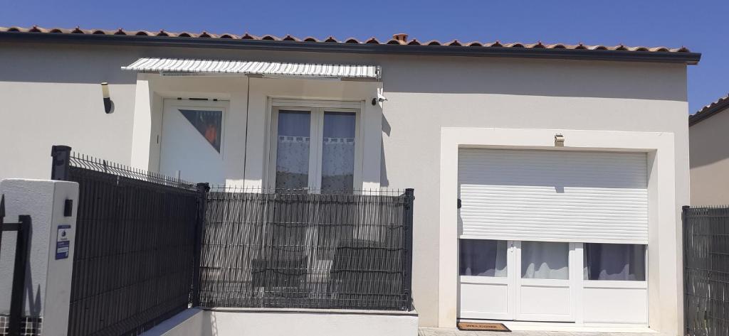 a white house with a gate and a fence at Chambre d'hôtes in Sigean