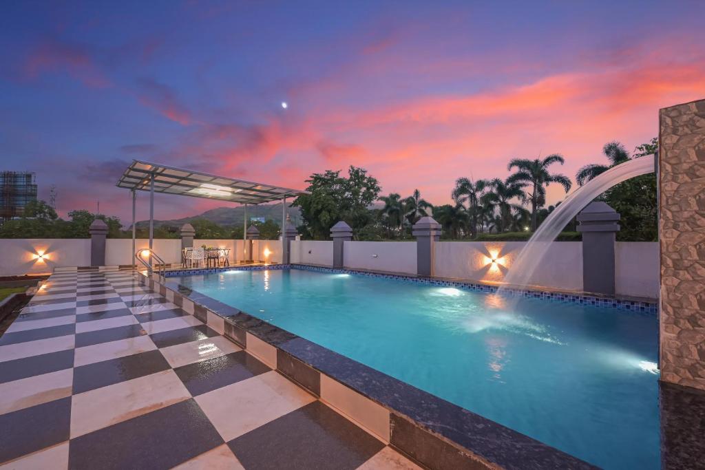 a swimming pool with a sunset in the background at Courtyard Villa by Tropicana Stays in Lonavala