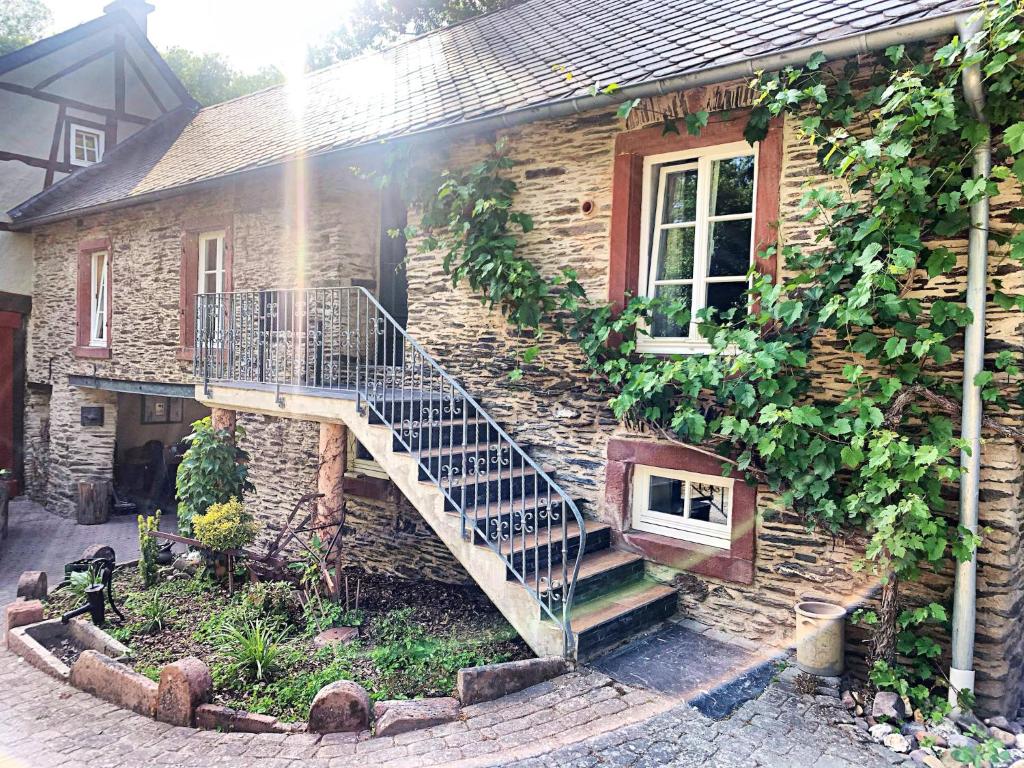a stone house with a staircase on the side of it at Mosel Mill Garden Stay in Maring-Noviand