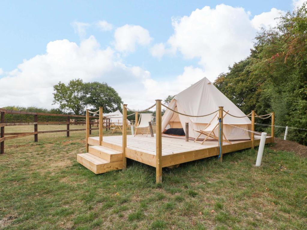 a tent with a wooden bed in a field at Bell 2 in Cirencester