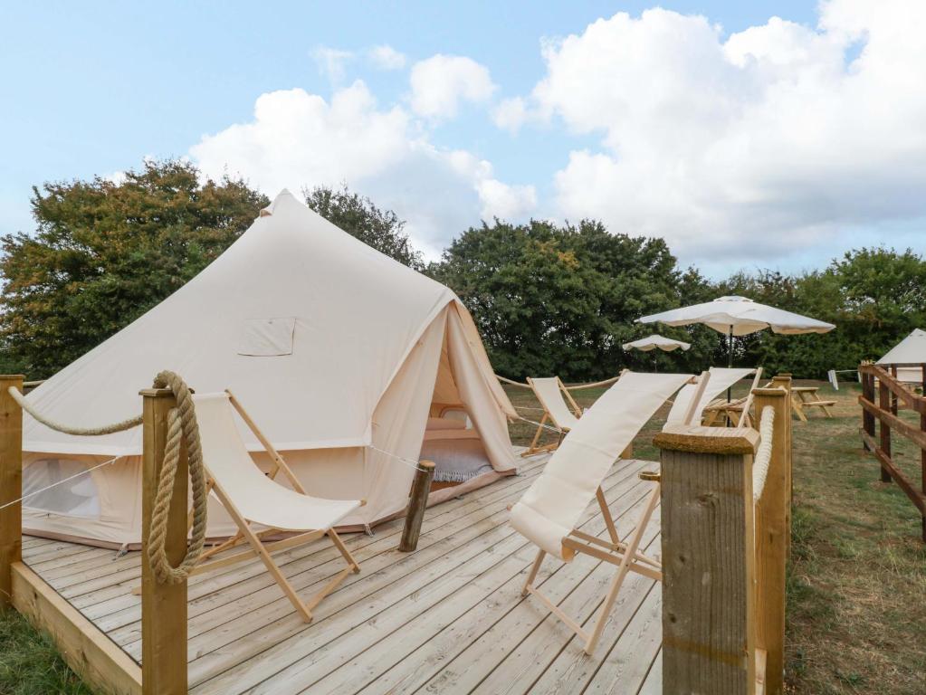 a yurt with chairs and umbrellas on a deck at Bell 1 in Cirencester