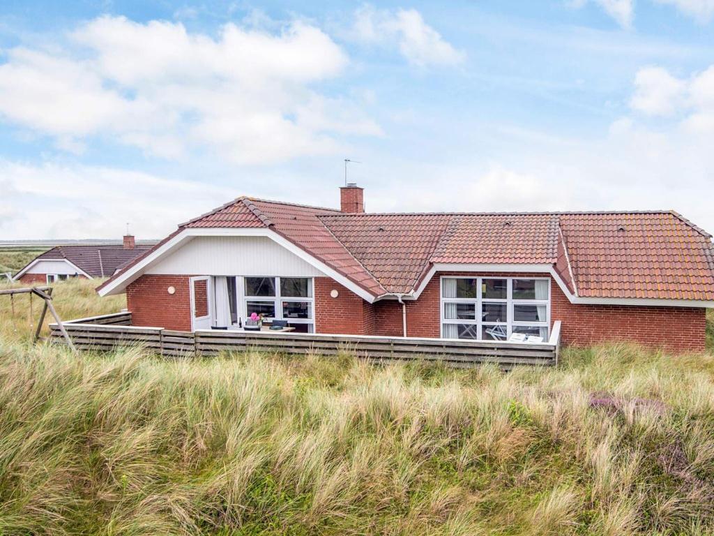 a red brick house on the side of a field at 5 star holiday home in Ringkøbing in Ringkøbing