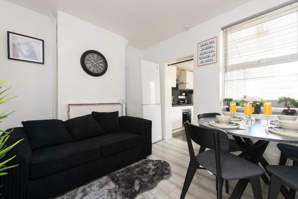 a living room with a black couch and a table at Comfort Meets Style, 4-Bedroom Home with All Essentials, Croydon, Sleeps 8! Contractor Friendly! in Thornton Heath