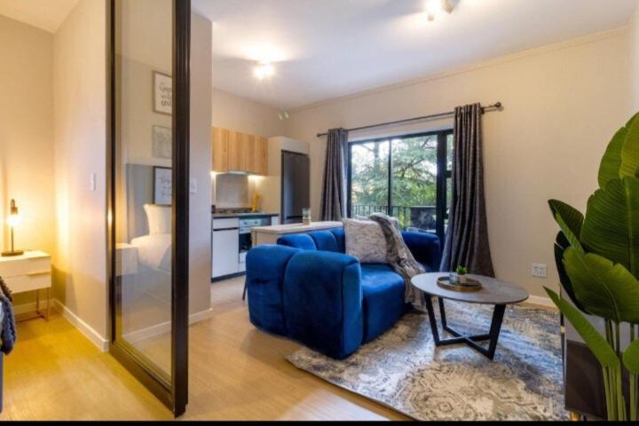 a living room with a blue couch and a table at #AlimamaSpaces The Thando's Akaru in Johannesburg