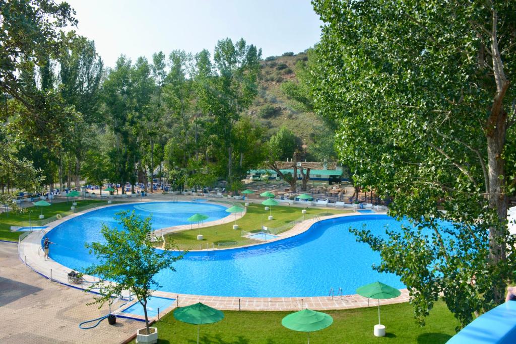 Una vista aérea de una gran piscina con sombrillas. en HOSTAL LA CAÑADA RUIDERA, en Ossa de Montiel