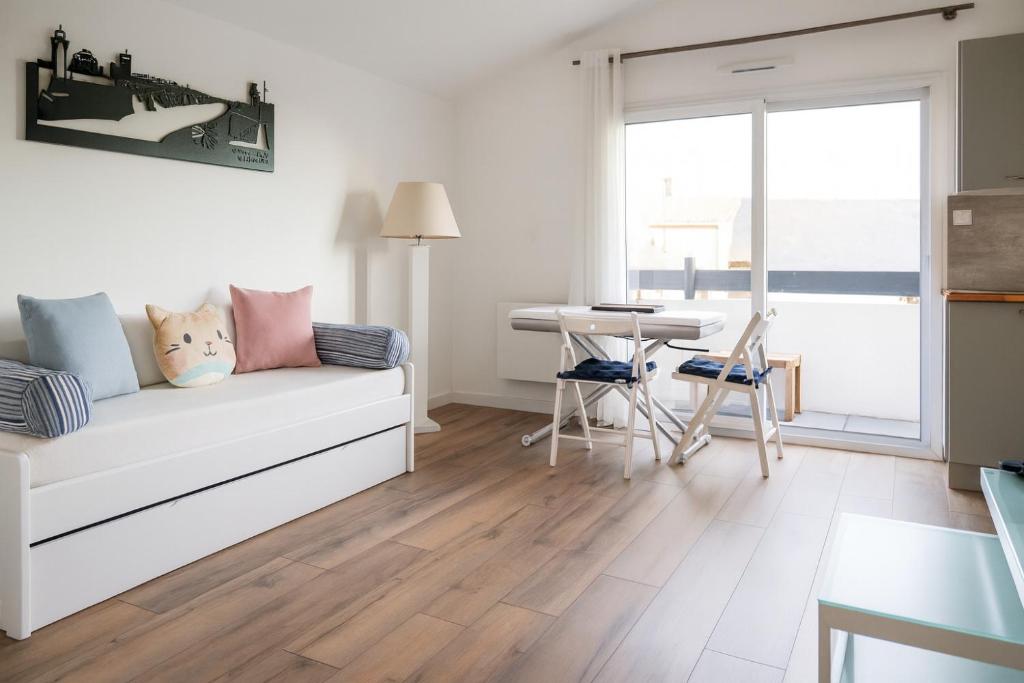 a living room with a white couch and a table at Joli studio avec balcon - 2 personnes in Les Sables-dʼOlonne