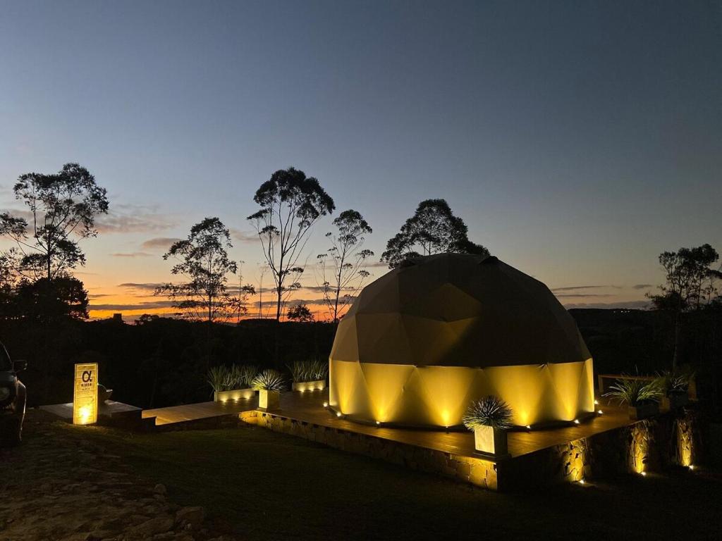 a black and yellow domed building with lights at dusk at Domo nas Alturas! Lareira, Hidro e Céu Estrelado in Rancho Queimado