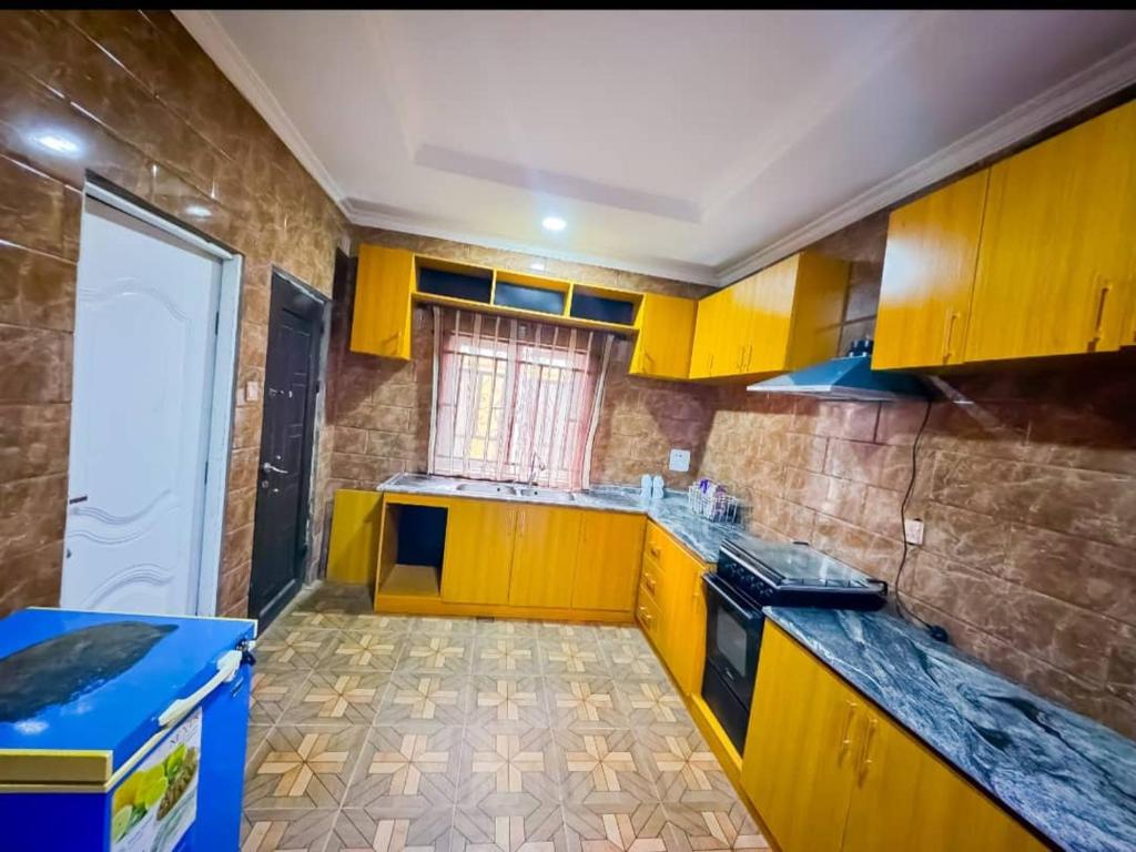una pequeña cocina con armarios amarillos y una ventana en Revolution Apartment Lemode Kobape abk, en Abeokuta