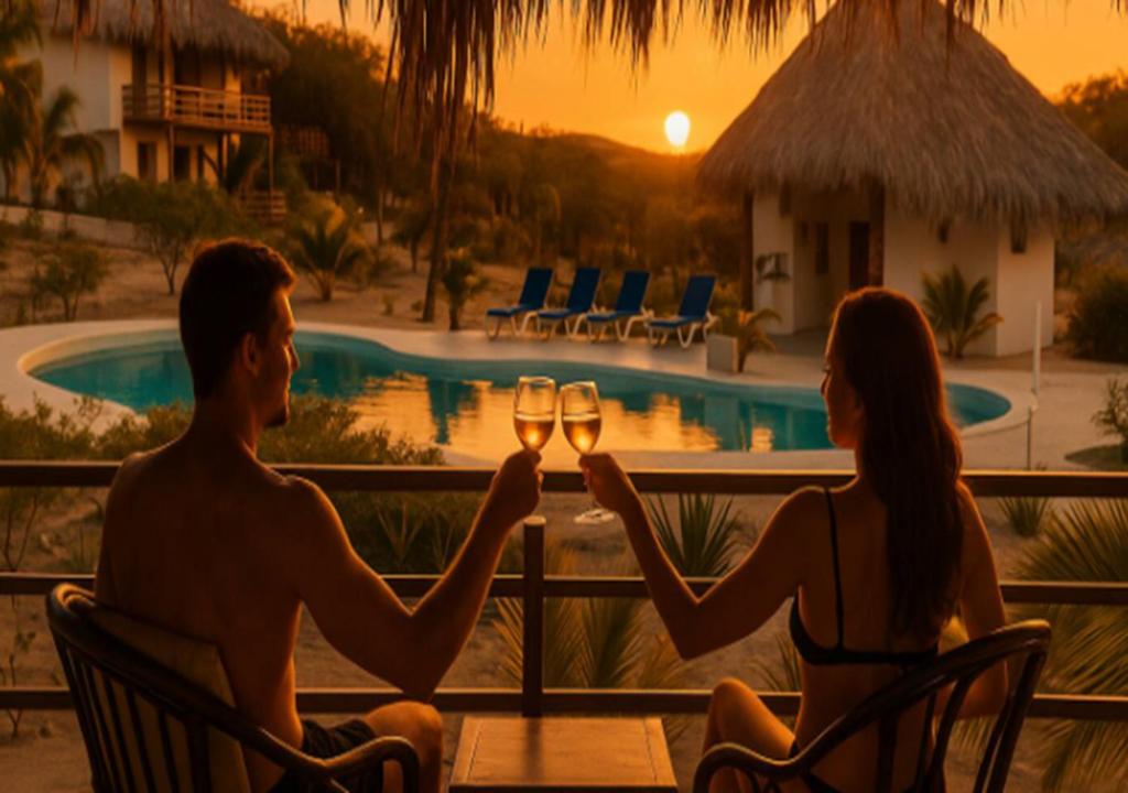 a man and woman sitting at a table with glasses of wine at Beach Home Organos Piura Family Vacations in Los Órganos