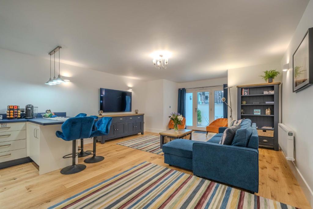 Una sala de estar con un sofá azul y una cocina. en Spacious Modern 2-bed Parking & Wi-Fi & 65"OLED, en Bristol