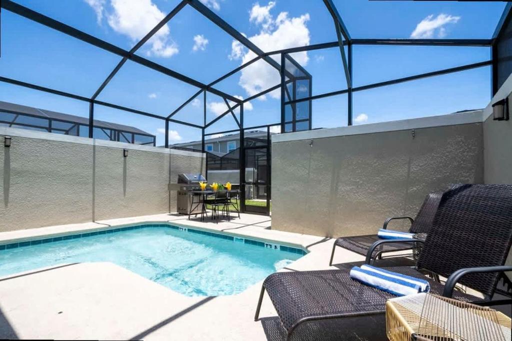 een zwembad met twee stoelen en een tafel bij Splendid 5Bd Close to Disney at Storey Lake 4251 in Kissimmee