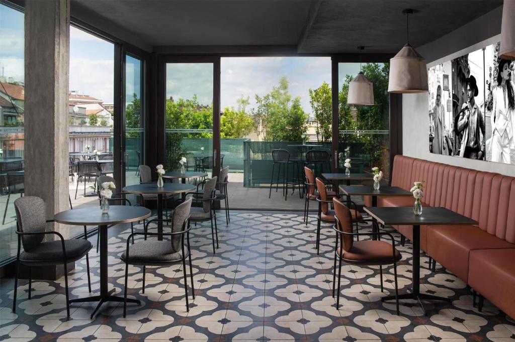 a restaurant with tables and chairs and large windows at NH Milano Corso Buenos Aires in Milan