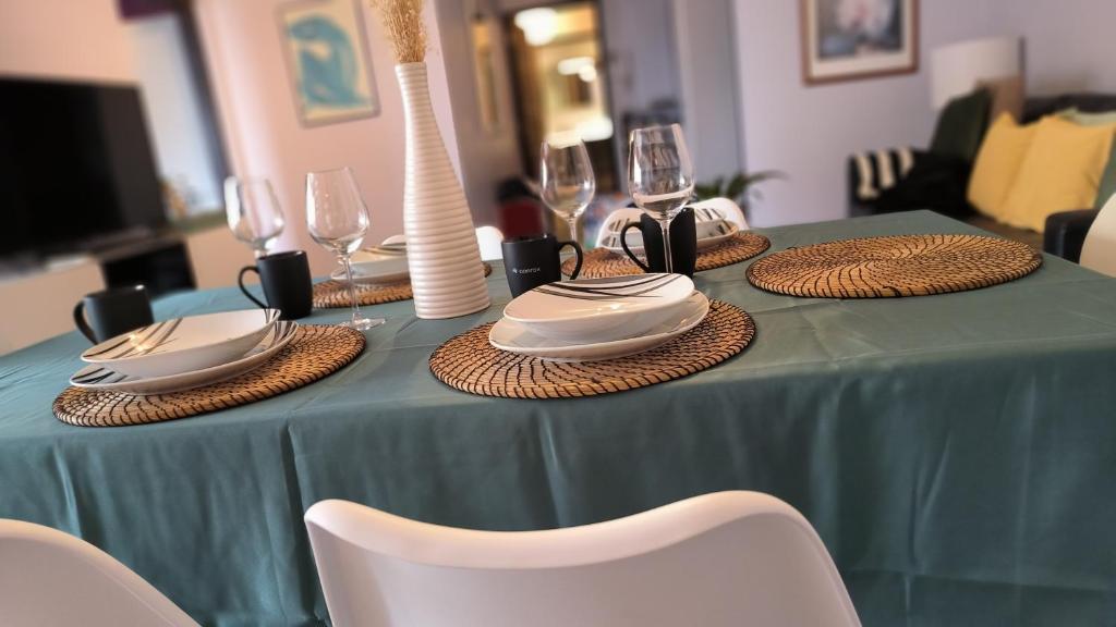 a table with a green table cloth with plates and wine glasses at Port Royal in Aix-en-Provence