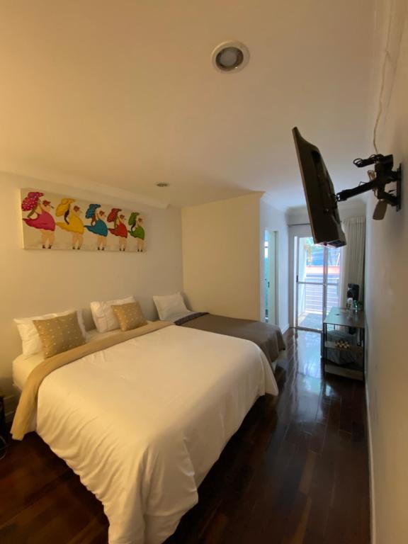 una camera da letto con un letto e una TV a schermo piatto di Suíte ampla e confortável a San Paolo