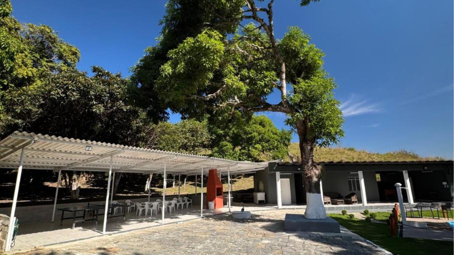 a tree in front of a building with tables and chairs at Seleto Hotel Express in Arrozal