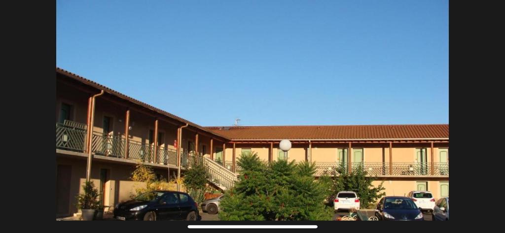 a building with cars parked in a parking lot at Abel Hôtel in Langeac
