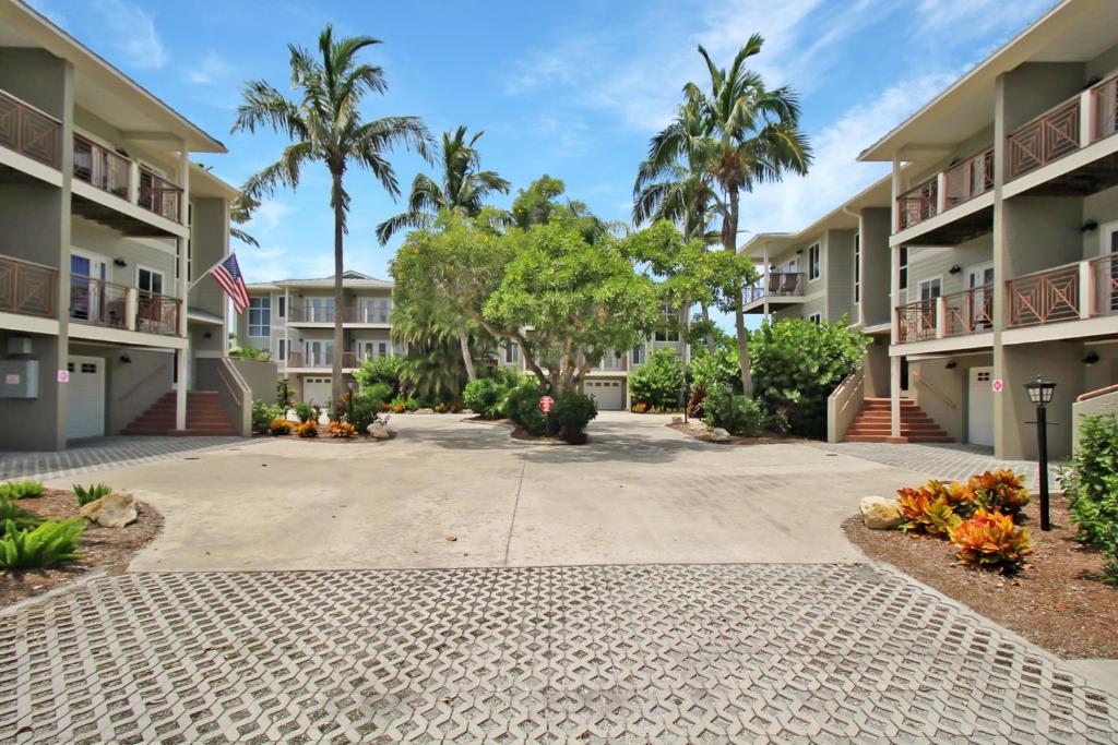 a driveway in front of apartment complexes with palm trees at Shell Yeah 3 Story Condo On AMI in Holmes Beach