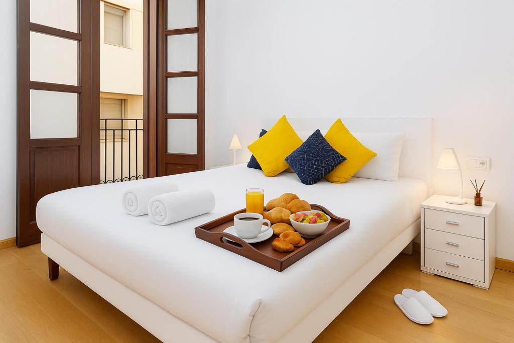 a bed with a tray of food on it at Grand Central Market Suites By VALENCIAFLATS EU in Valencia