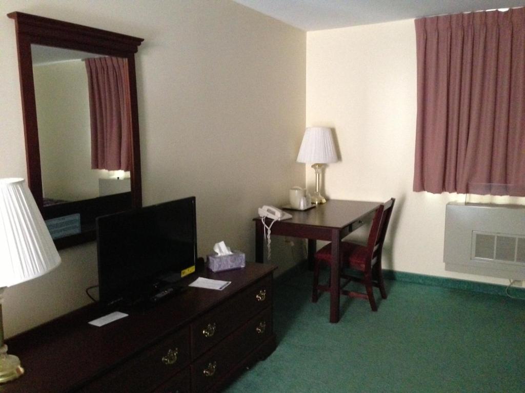 a hotel room with a desk and a television at The Falls Motel in Watkins Glen