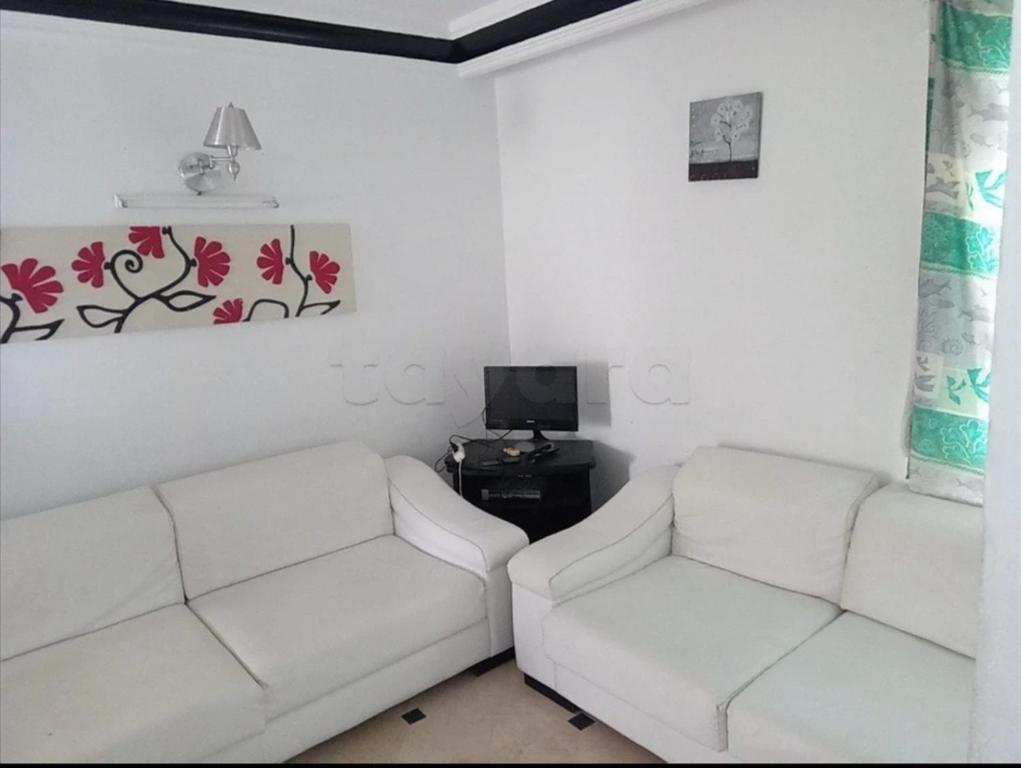 sala de estar con 2 sofás blancos y TV en Hammam sousse, en Hammam Sousse