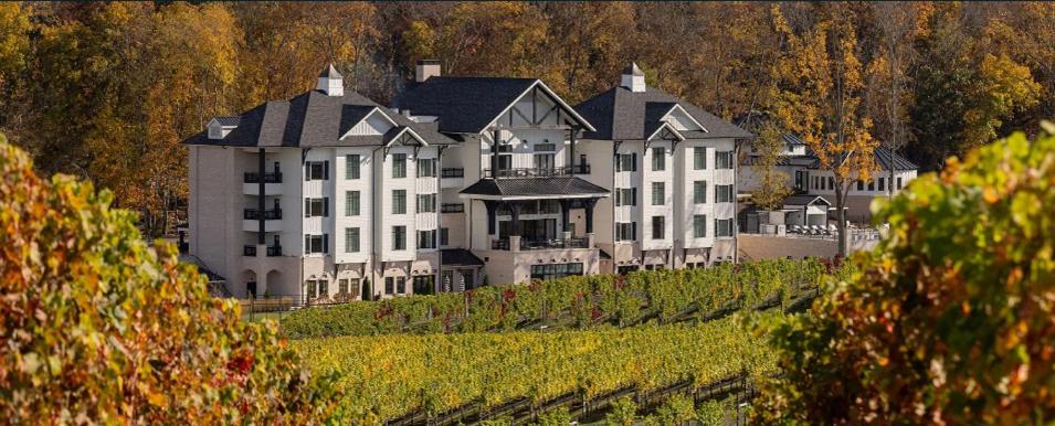 a large white building on a hill with trees at Nicewonder Farm & Vineyards in Bristol