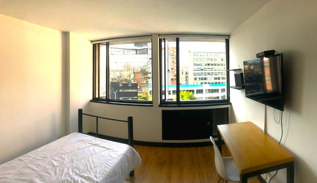 a bedroom with a bed and a desk and a window at Habitaciones junto a Clinica Marly in Bogotá